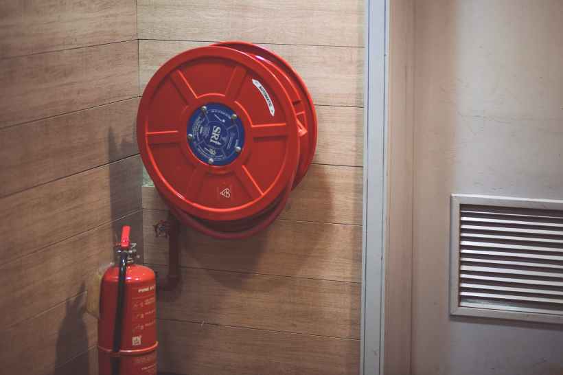 red fire extinguisher beside hose reel inside the room